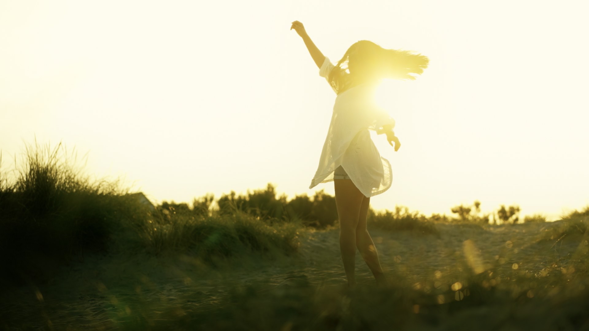 Graded frame: woman dancing on a beach in warm golden backlight